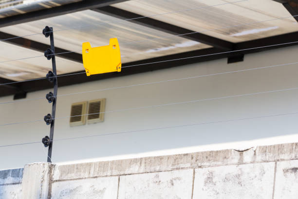 high voltage security electric fence on concrete wall oh house, blank yellow sign hang on electric fence